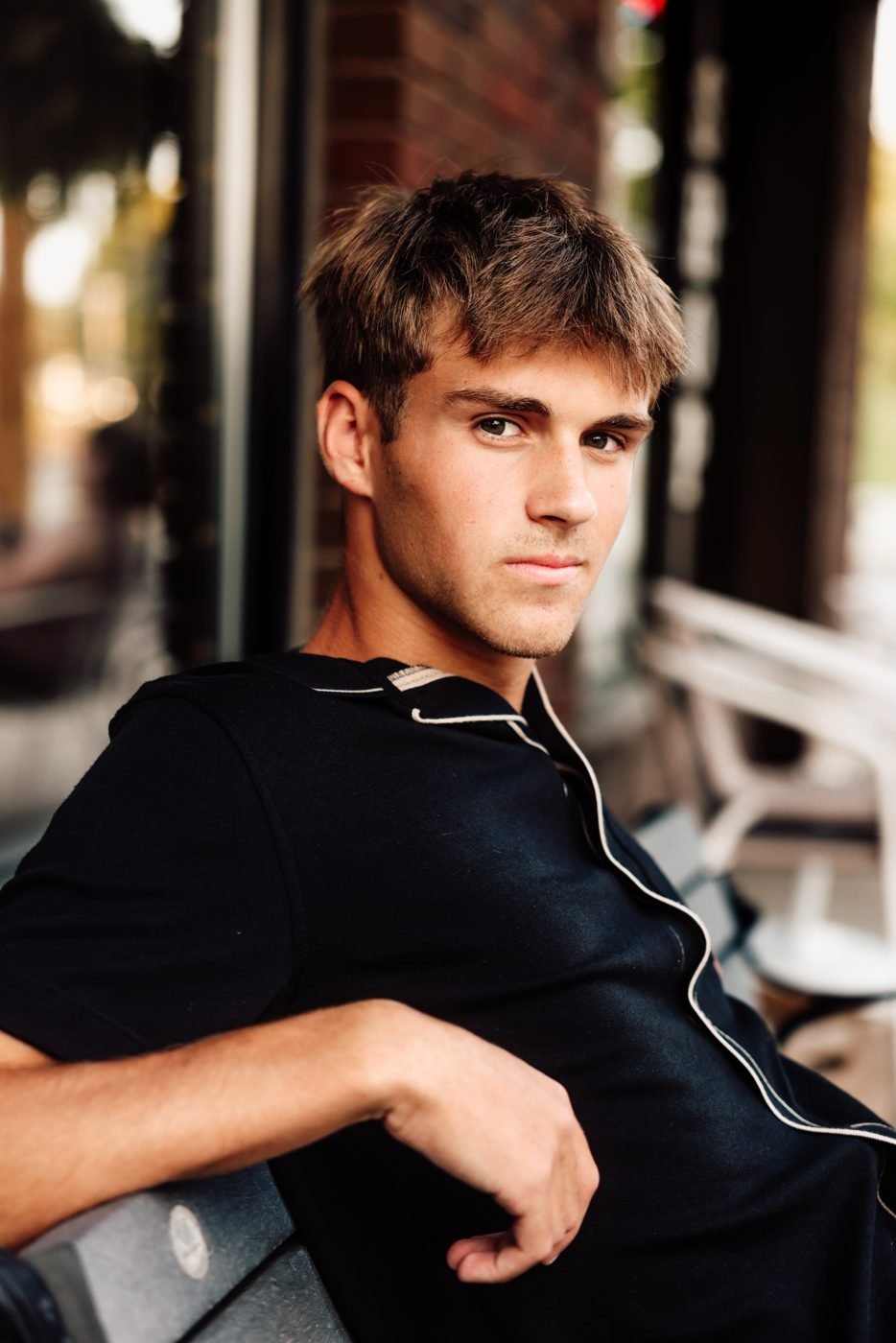 Senior portrait of a young man seated on a downtown bench